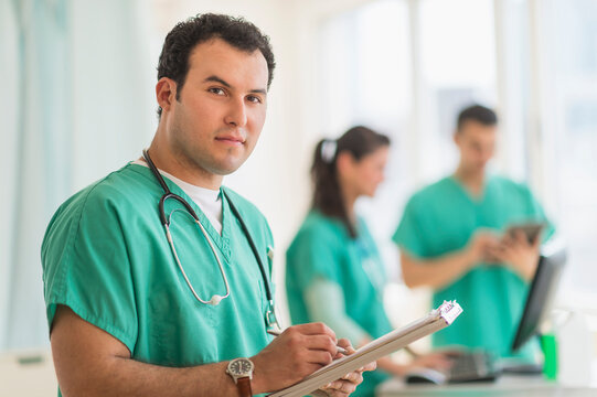 Hispanic nurse reading medical chart in hospital