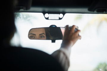 Caucasian woman adjusting rear view mirror in car