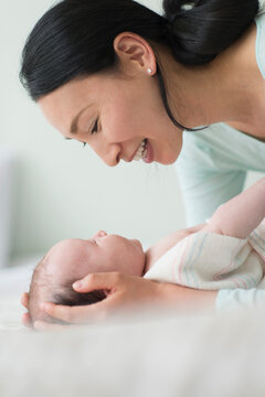 Asian mother holding baby on bed