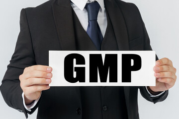 Obraz premium A businessman holds a sign in his hands which says GMP - GOOD MANUFACTURING PRACTICE