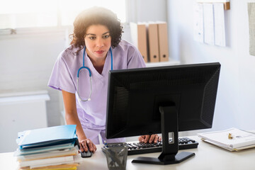 Mixed race nurse using computer in office