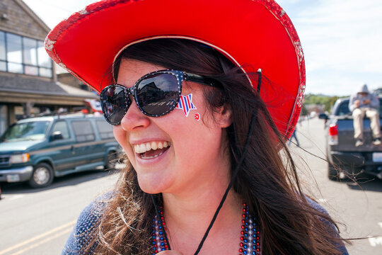 Caucasian woman wearing cowboy hat and face paint in street