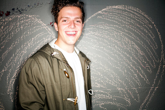 Caucasian man smiling near chalk heart on wall