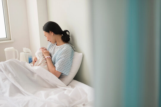 Asian mother holding newborn baby in hospital