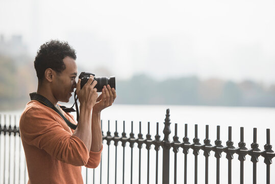 Mixed race man taking photograph on waterfront