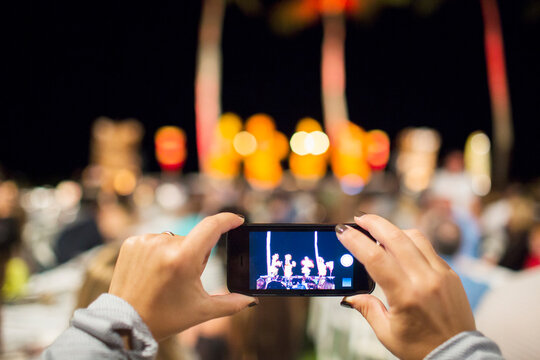 Close up of woman photographing hula dancers at luau
