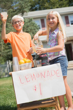 Caucasian children selling lemonade in front yard