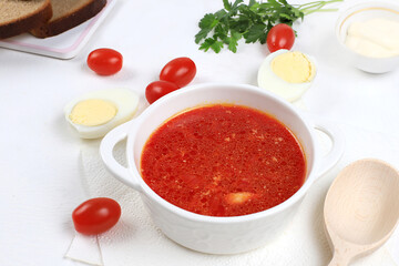 Traditional Russian borsch with parsley and bread on a light table, business card for the menu, natural products and ingredients, healthy food concept, rustic style, selective approach.