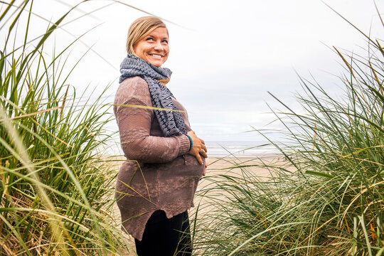 Caucasian pregnant woman holding her stomach on beach