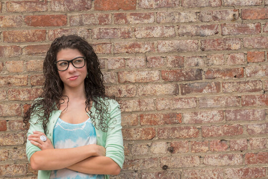 Pensive mixed race woman standing with arms crossed