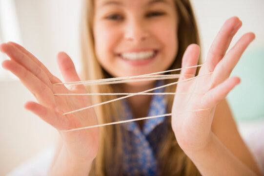Caucasian girl playing cats cradle game