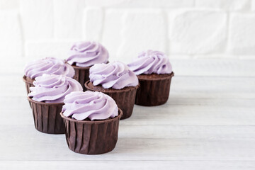 Delicious muffins with lilac cream on a light background.
