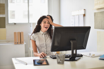 Mixed race businesswoman gasping at computer at desk in office