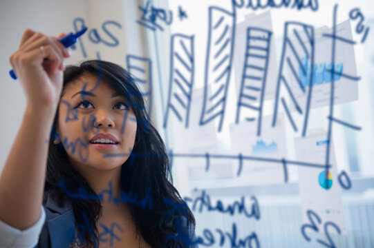 Pacific Islander businesswoman drawing chart on glass in office
