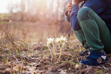 Mari boy crouching near flowers in forest