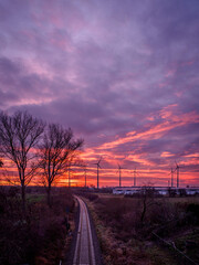 Fototapeta na wymiar a dramatic sunrise colors the sky purple and in the foreground railroad tracks