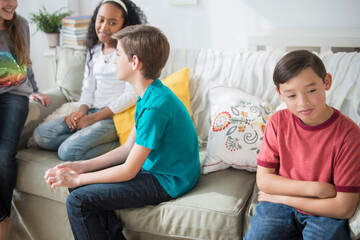 Pouting boy ignoring friends in living room