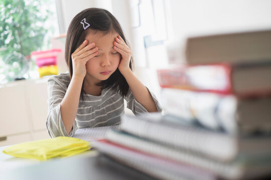Anxious Chinese student rubbing forehead doing homework