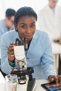 Scientist using microscope and digital tablet in research laboratory