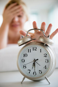 Caucasian woman shutting off alarm clock
