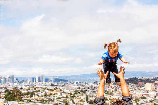 Caucasian father tossing daughter over San Francisco cityscape, California, United States
