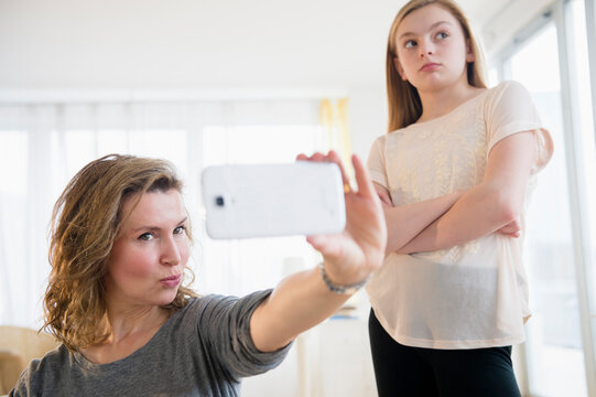 Caucasian girl embarrassed of mother taking selfies with cell phone