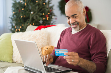 Mixed race man shopping online with laptop at Christmas