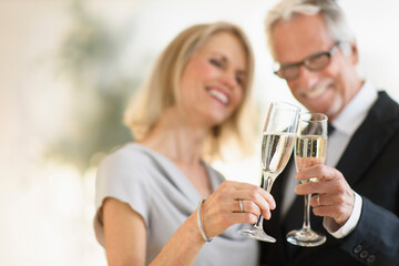 Smiling older Caucasian couple toasting with champagne