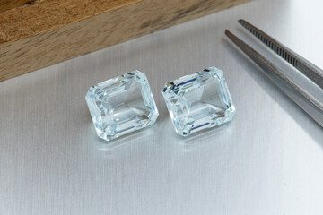 macro mineral faceted stone aquamarine with tweezers on a gray background