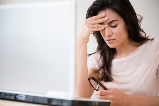 Stressed woman rubbing her forehead at laptop
