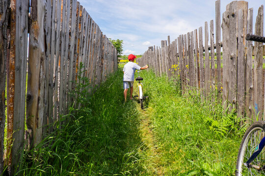 Mari boy pushing bicycle between fences
