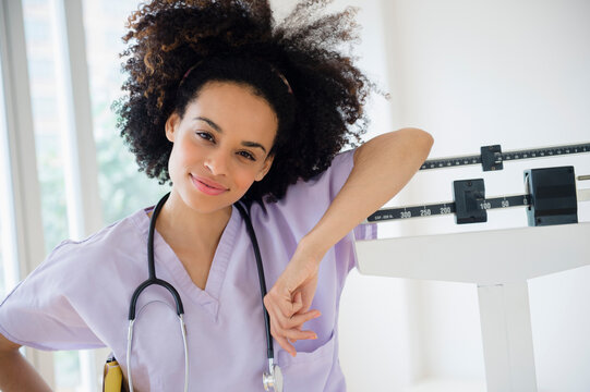 Mixed race nurse leaning on scale