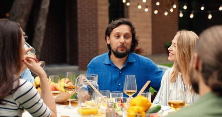 Happy Caucasian cheerful family with kids and grandfather having lunch picnic at back yard outdoors and nice communication. People of different ages spending time together at barbecue.