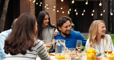 Happy Caucasian cheerful family with kids and grandfather having lunch picnic at back yard outdoors and nice communication. People of different ages spending time together at barbecue.