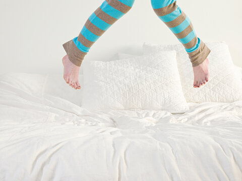 Caucasian woman jumping on bed