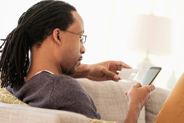 Black man shopping with cell phone on sofa