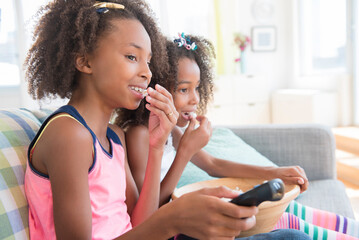 Mixed race sisters watching television on sofa