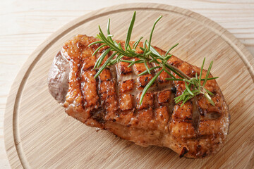 Crispy roasted duck breast with rosemary garnish on a wooden chopping board, high angle view from above