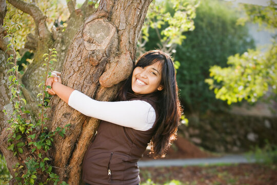 Hispanic woman hugging tree