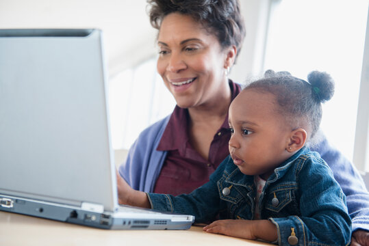 Black grandmother and granddaughter using laptop