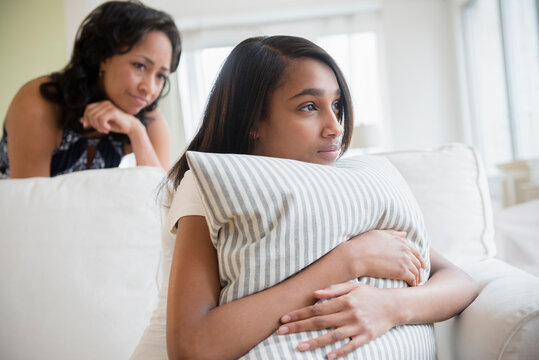 Mother watching pensive daughter clutching pillow