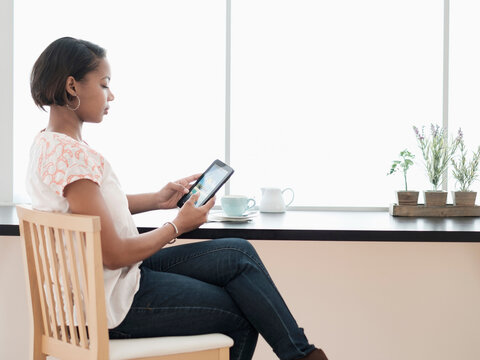 Black woman using digital tablet at coffee shop near window