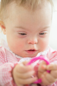 Caucasian baby girl with Down Syndrome playing with ring