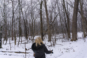 Blonde woman catches snowflakes in forest