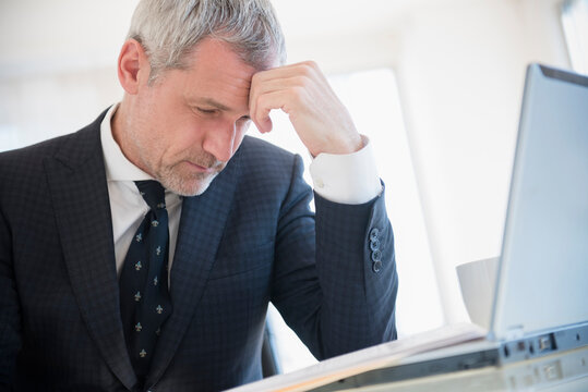 Frustrated older Caucasian businessman using laptop