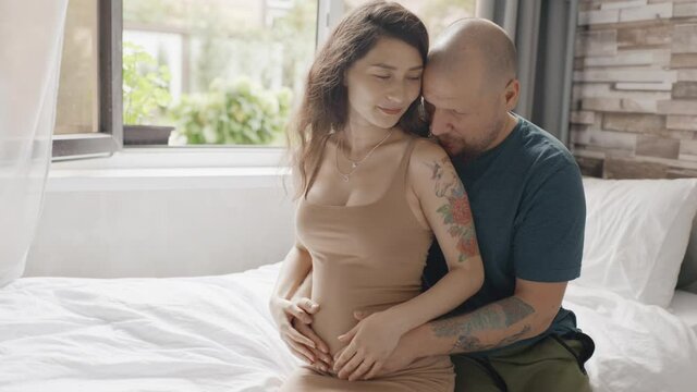 Couple expecting baby and petting belly. Man kissing his pregnant wife. Tender intimacy moment of love. New family birth. Concept of motherhood and happiness. Futere mom and dad.