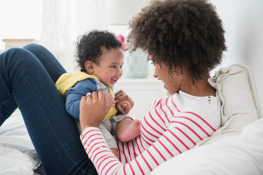 Mother Holding Baby Son In Lap On Bed