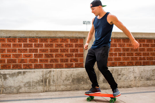 Caucasian man skateboarding near brick wall
