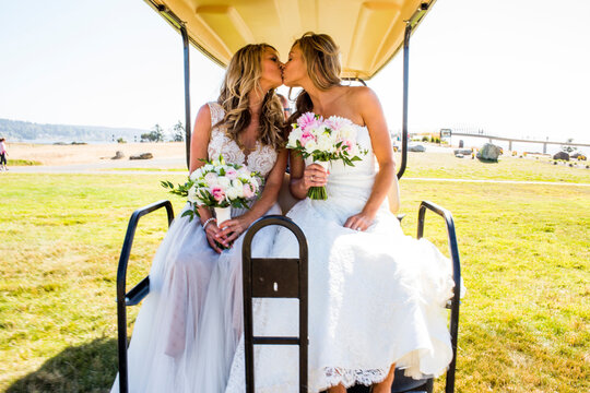 Caucasian brides kissing in golf cart