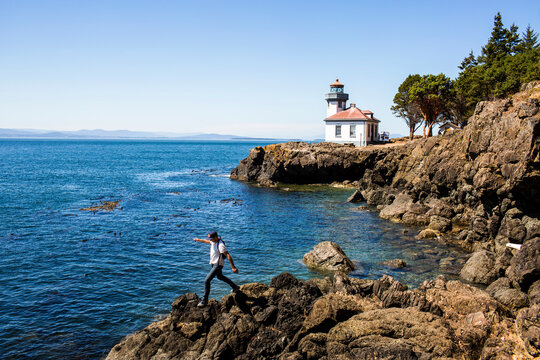 Caucasian man walking on rocks near lighthouse